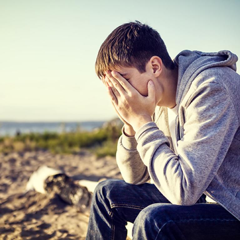 Ung kille håller händerna för ansiktet